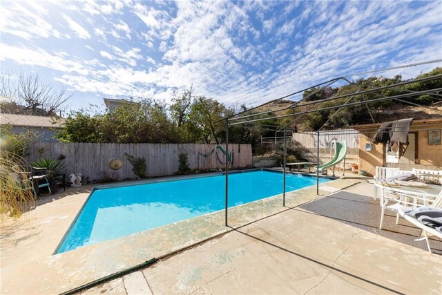 view of swimming pool with a patio area, a fenced backyard, a fenced in pool, and a water slide