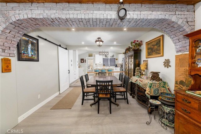 dining space featuring light wood finished floors and a barn door