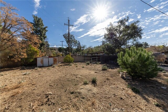 view of yard with an outdoor structure, a storage shed, and fence