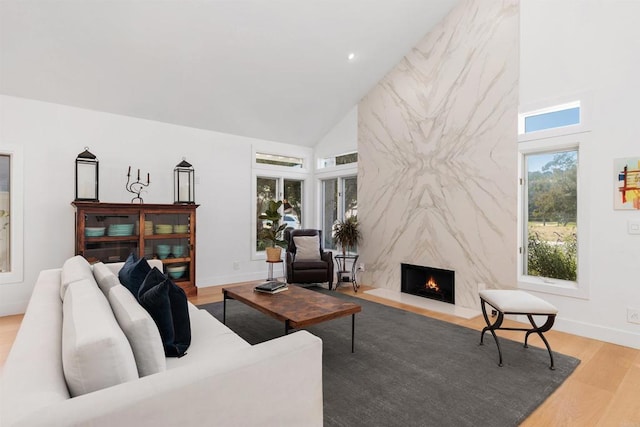 living room featuring a fireplace, light hardwood / wood-style flooring, and high vaulted ceiling