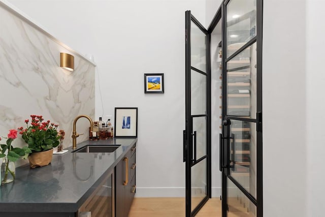 bar featuring beverage cooler, light hardwood / wood-style floors, and sink