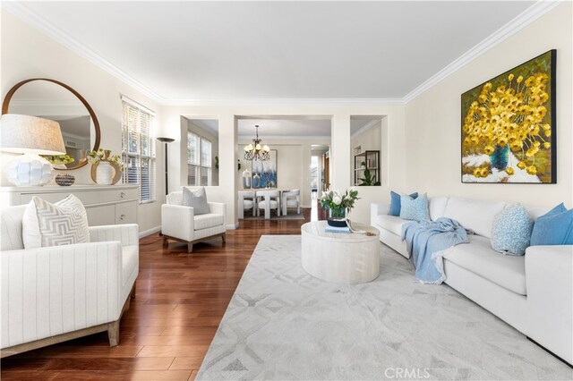 living room with an inviting chandelier, ornamental molding, and dark hardwood / wood-style floors