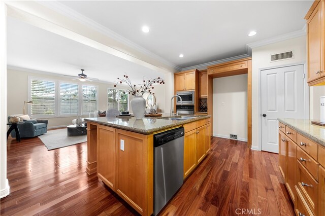 kitchen featuring light stone countertops, appliances with stainless steel finishes, a kitchen island with sink, and sink