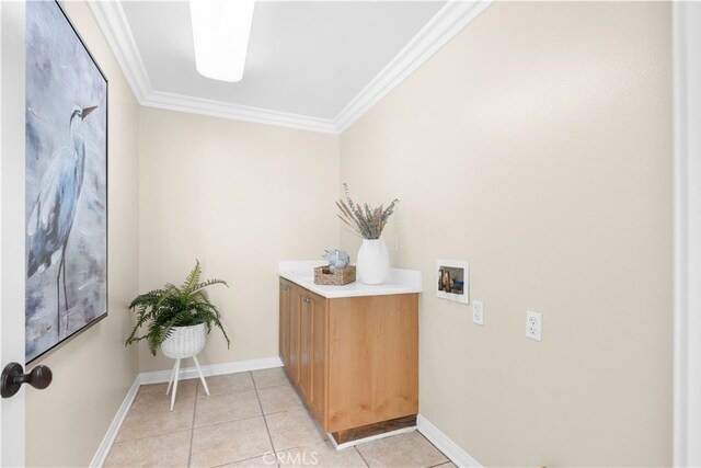 washroom featuring hookup for a washing machine, crown molding, light tile patterned floors, and cabinets