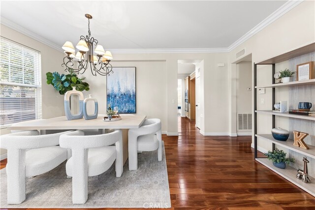 dining room with dark hardwood / wood-style flooring, crown molding, and an inviting chandelier