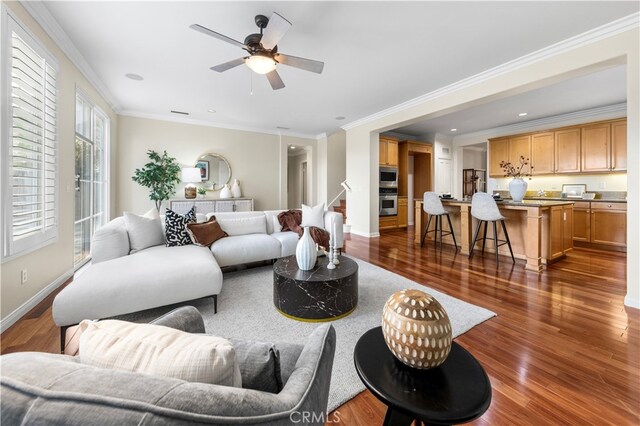 living room with dark wood-type flooring, ceiling fan, and crown molding