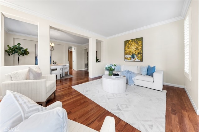 living room with dark wood-type flooring, ornamental molding, and an inviting chandelier