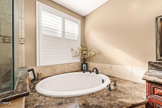 bathroom featuring tiled tub and vanity