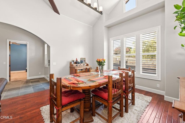 dining space with dark wood-type flooring, an inviting chandelier, and high vaulted ceiling