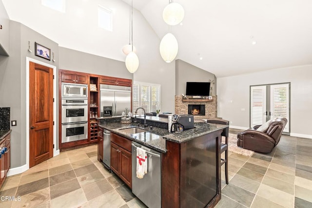 kitchen featuring a kitchen bar, sink, built in appliances, an island with sink, and pendant lighting