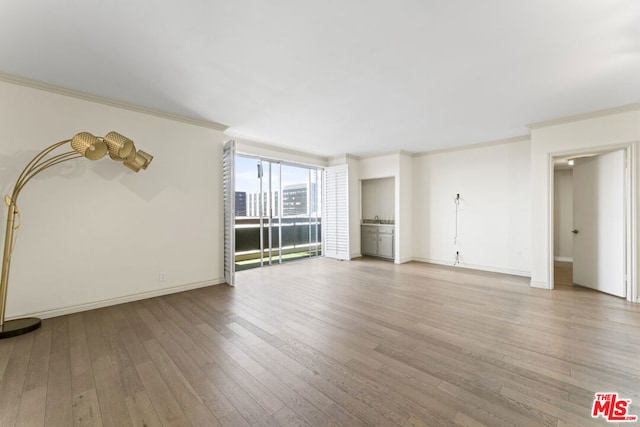 unfurnished living room with crown molding and light hardwood / wood-style floors