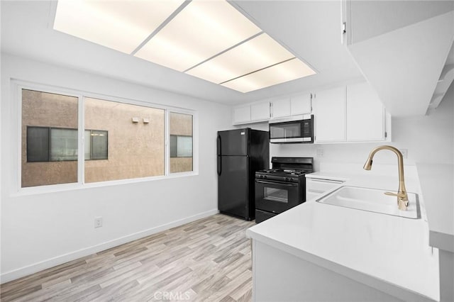 kitchen featuring a healthy amount of sunlight, sink, white cabinets, and black appliances