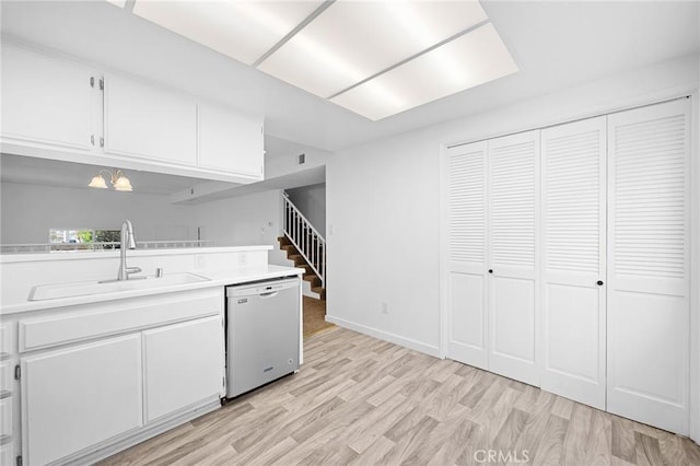 kitchen featuring white cabinetry, sink, stainless steel dishwasher, and light hardwood / wood-style floors