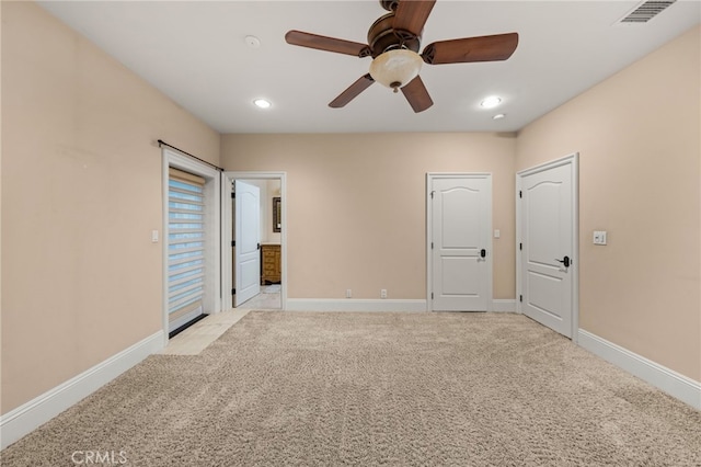 unfurnished bedroom featuring ceiling fan, light colored carpet, and ensuite bathroom