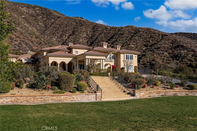 mediterranean / spanish-style home with a mountain view and a front lawn