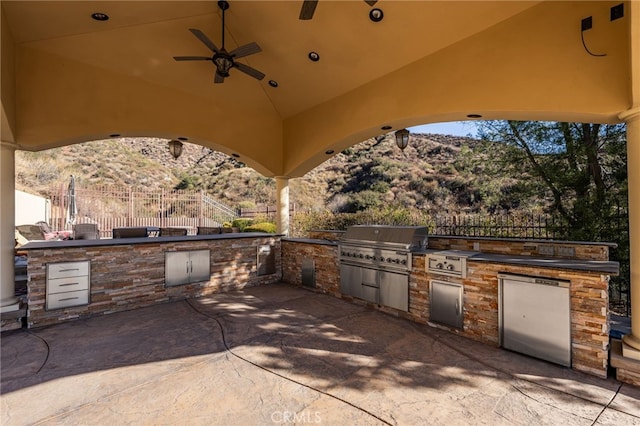 view of patio / terrace with exterior kitchen, ceiling fan, a grill, and a mountain view