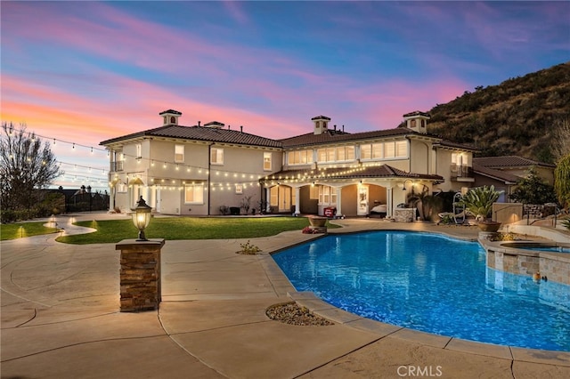 exterior space with a swimming pool with hot tub, a balcony, and a patio area