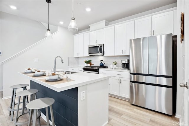 kitchen with sink, stainless steel appliances, an island with sink, and white cabinets