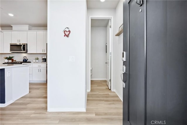 kitchen with tasteful backsplash, light hardwood / wood-style floors, and white cabinets