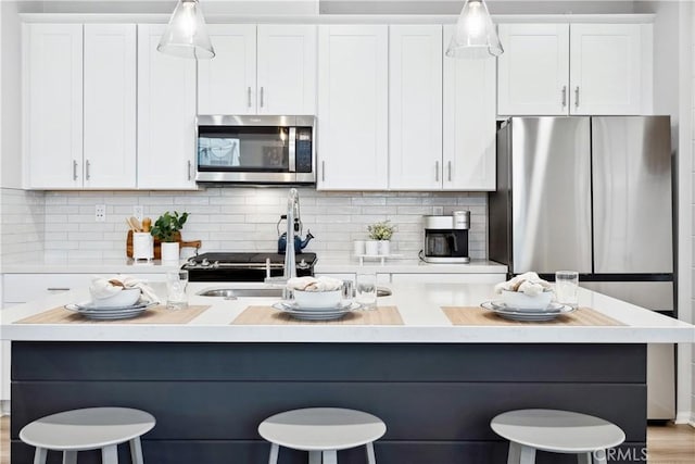 kitchen with stainless steel appliances, white cabinets, and a kitchen bar