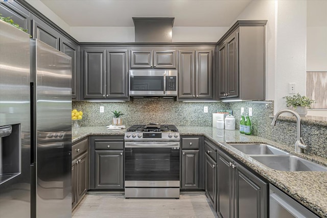 kitchen featuring light stone counters, sink, backsplash, and stainless steel appliances