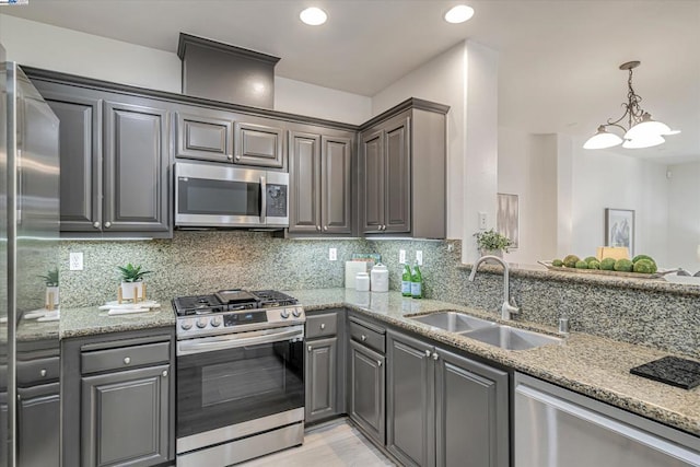 kitchen with tasteful backsplash, appliances with stainless steel finishes, sink, and light stone counters