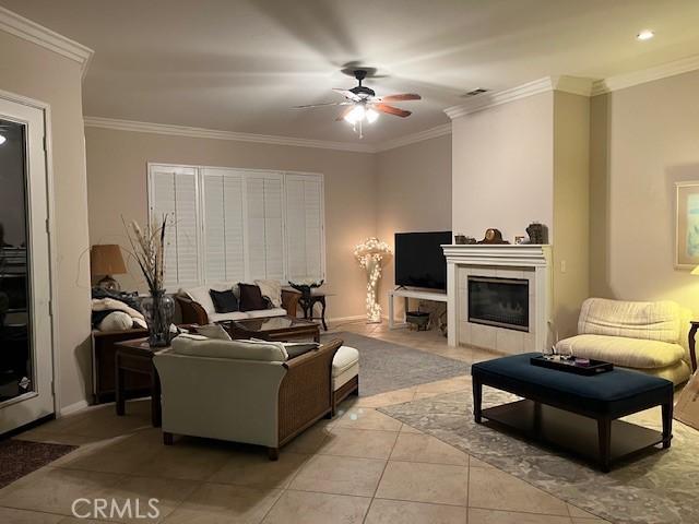 living room featuring crown molding, light tile patterned floors, and a fireplace