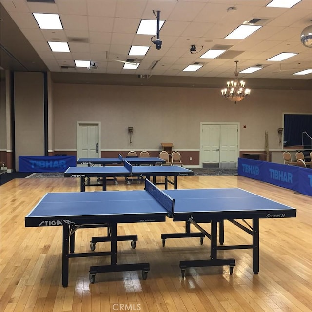 rec room with a drop ceiling, wood-type flooring, and a towering ceiling