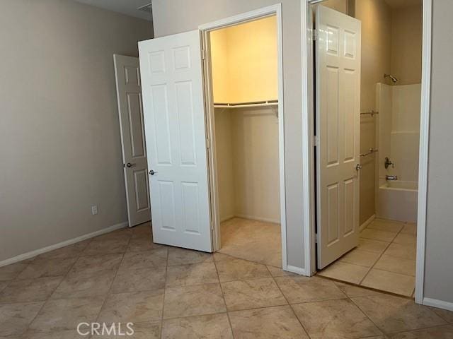 5467 Breckenridge Ave, Banning, CA 92220 - unfurnished bedroom featuring light tile patterned floors, a walk in closet, a closet, and ensuite bath