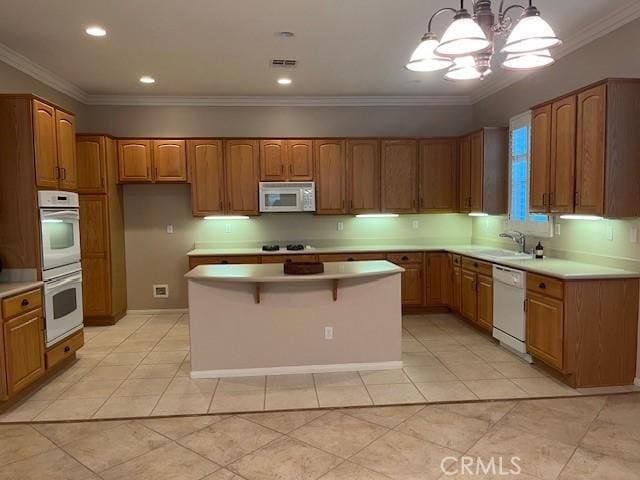 kitchen featuring brown cabinets, white appliances, light countertops, and hanging light fixtures