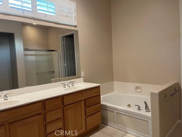 bathroom featuring double vanity, tile patterned floors, a sink, and a whirlpool tub