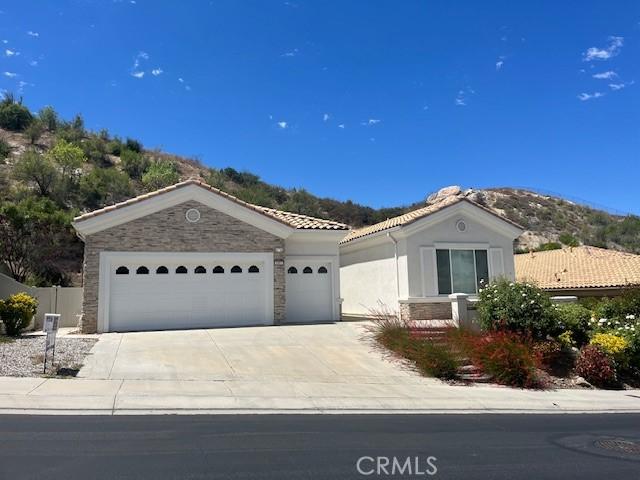 5467 Breckenridge Ave, Banning, CA 92220 - view of front facade with stone siding, a garage, a tile roof, concrete driveway, and stucco siding