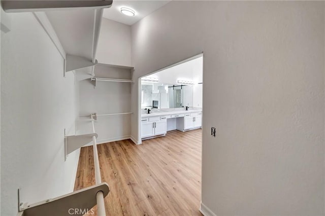 walk in closet with light hardwood / wood-style flooring