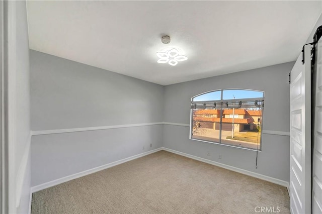 carpeted spare room featuring a barn door