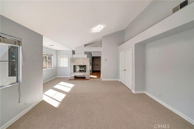 unfurnished living room with light colored carpet, a premium fireplace, and vaulted ceiling