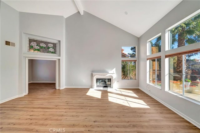 unfurnished living room with beamed ceiling, high vaulted ceiling, and light wood-type flooring