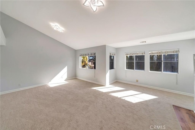 empty room featuring vaulted ceiling and light colored carpet