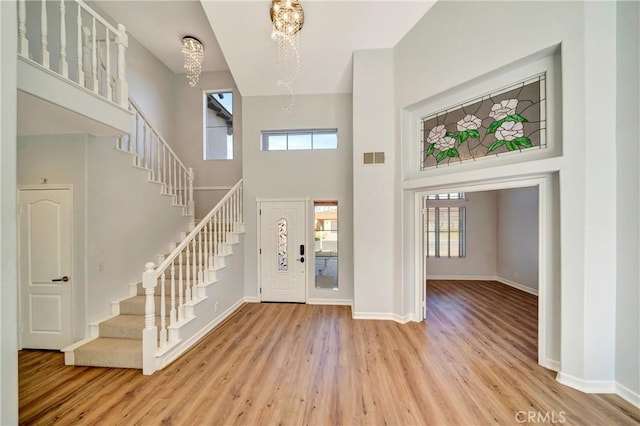 entrance foyer featuring a chandelier, light hardwood / wood-style flooring, and a high ceiling