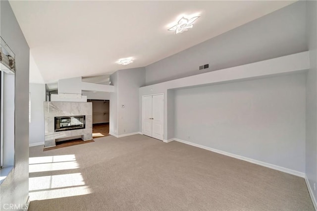 unfurnished living room featuring a high end fireplace, high vaulted ceiling, and carpet