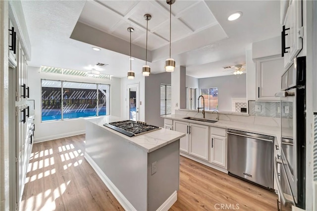 kitchen featuring sink, appliances with stainless steel finishes, light stone counters, white cabinets, and kitchen peninsula