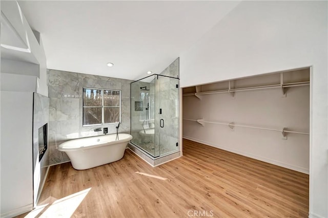 bathroom with hardwood / wood-style flooring, shower with separate bathtub, and tile walls