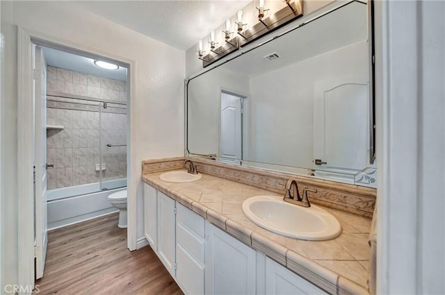 full bathroom with wood-type flooring, toilet, combined bath / shower with glass door, and vanity