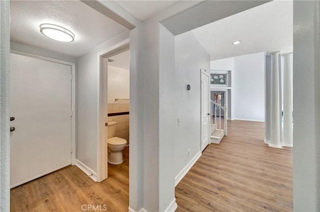 hall with light hardwood / wood-style flooring and ornate columns