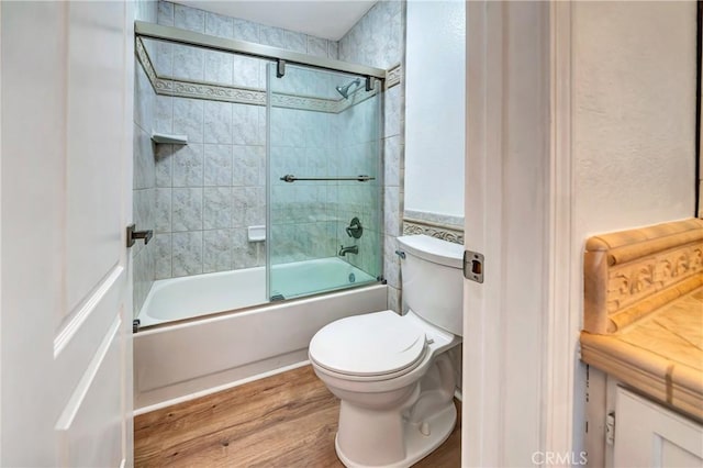 bathroom featuring hardwood / wood-style flooring, shower / bath combination with glass door, and toilet