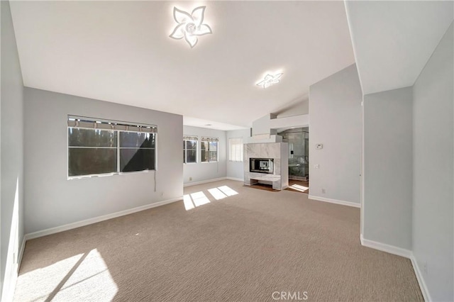 unfurnished living room with vaulted ceiling, carpet, and a high end fireplace