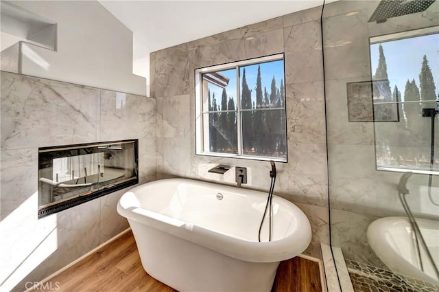 bathroom featuring vaulted ceiling, tile walls, hardwood / wood-style flooring, separate shower and tub, and a premium fireplace