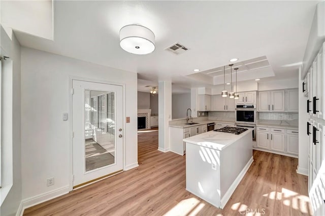 kitchen featuring sink, hanging light fixtures, white cabinets, a kitchen island, and a raised ceiling