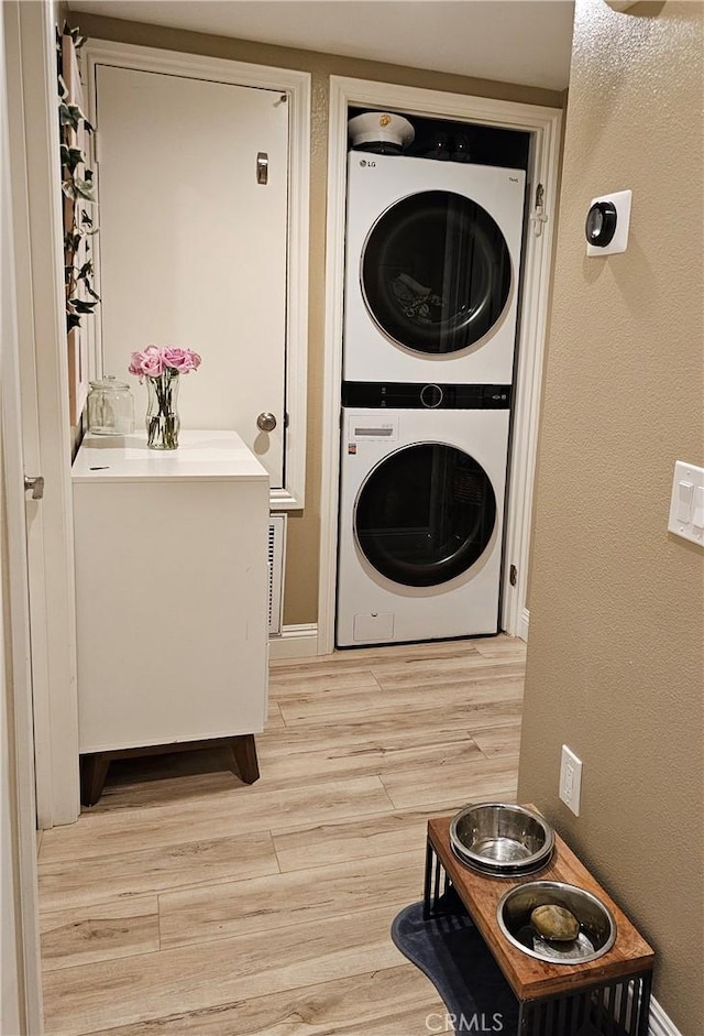 clothes washing area with stacked washer / drying machine and light hardwood / wood-style floors