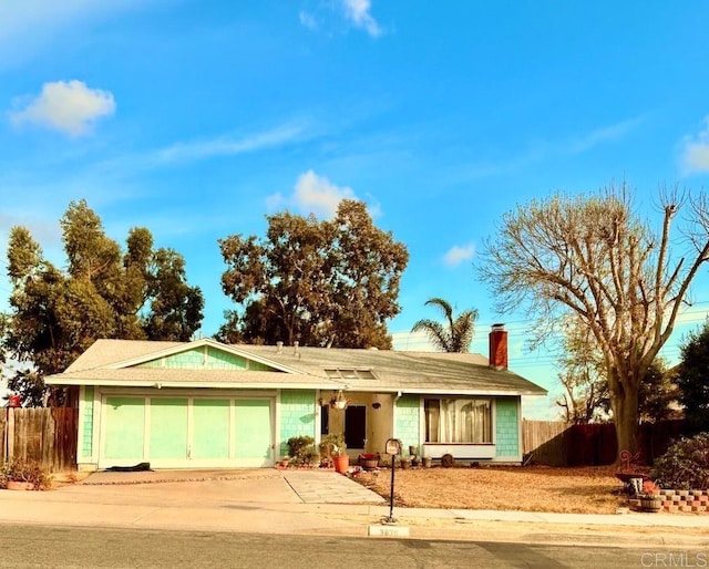 ranch-style house with driveway, an attached garage, a chimney, and fence