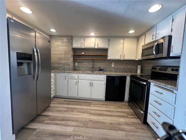 kitchen featuring light wood finished floors, a sink, white cabinets, appliances with stainless steel finishes, and tasteful backsplash